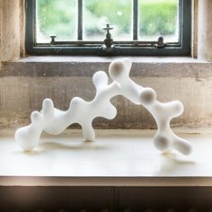 two white vases sitting on top of a window sill