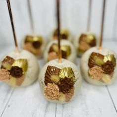 some cake pops are decorated with flowers and gold foil on top of white wood planks