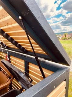 the inside of a wooden structure with pots on it and a sky in the background