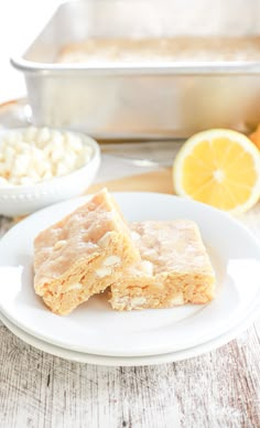 two pieces of cake on a white plate next to some lemons and other ingredients