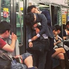 people are sitting on the subway and one person is covering his face with his hands