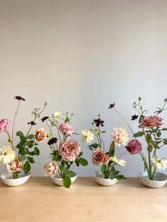 five vases filled with flowers on top of a wooden table