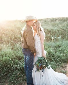 a bride and groom standing in the grass at their rustic wedding ceremony with sun shining on them