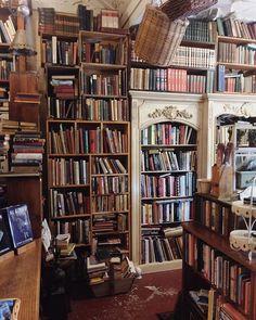 a room filled with lots of books on top of shelves next to a desk and chair