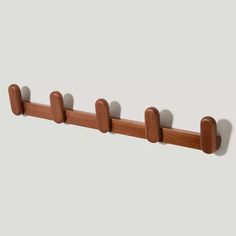 a wooden coat rack with five hooks on it's sides and four pegs attached to the wall