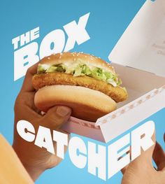 a person holding a box with a sandwich in it and the words catcher written on it