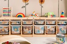 a child's room with sunflowers on the wall and toys in bins