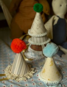 three small party hats sitting on top of a bed next to stuffed animals and teddy bears