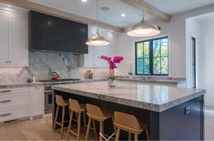 a kitchen with marble counter tops and stools next to an island in the middle