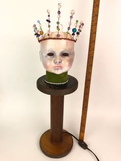 a white mask with beads on it sitting on top of a table next to a ruler