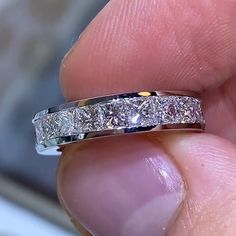 a person holding a wedding ring in their left hand with three diamonds on the band