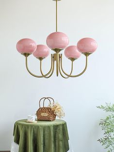 a pink chandelier hanging from the ceiling over a table with a green cloth on it