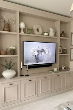 a flat screen tv sitting on top of a wooden shelf in front of a wall