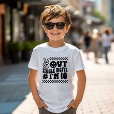 a young boy wearing sunglasses standing on the sidewalk