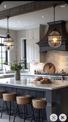 a kitchen island with stools in front of it and lights hanging from the ceiling