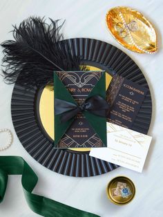 a black and gold wedding stationery on a plate next to some green satin ribbons