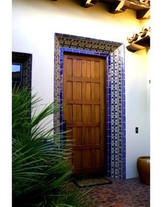 a wooden door sitting in front of a white wall next to a potted plant