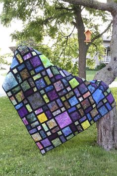 a quilt hanging from a tree in the grass