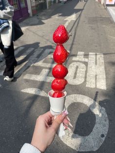 a person is holding a cup with strawberries on it in the middle of an empty street