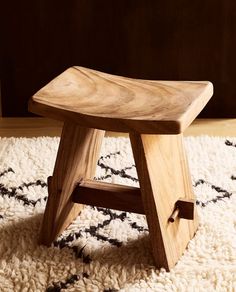 a wooden stool sitting on top of a rug