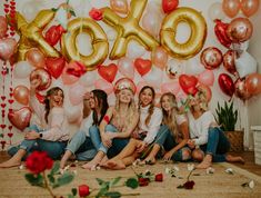 a group of women sitting next to each other in front of balloons