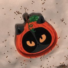 an orange and black pumpkin shaped object sitting on top of a white sheet with gold stars