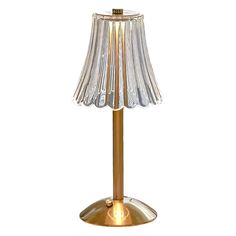 a gold table lamp with a glass shade on it's base and a light bulb in the middle