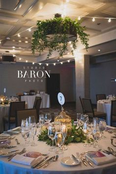 the table is set for an event with place settings and silverware, as well as greenery