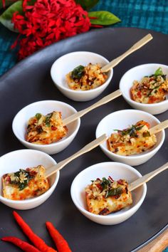 several small white bowls filled with food on top of a black plate