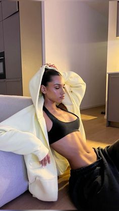 a woman laying on top of a couch next to a white jacket and black pants