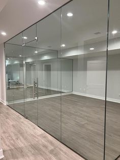 an empty room with glass walls and hard wood flooring in the center is shown