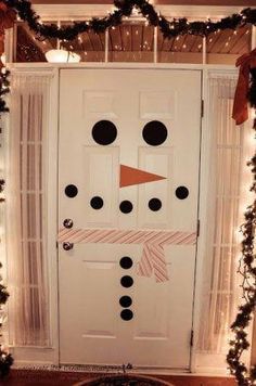 a decorated door with a snowman face on it and garlands around the edges