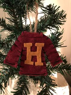 an ornament hanging from a christmas tree with the letter h on it's sweater