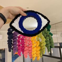 a hand holding up a crocheted eye shaped mirror