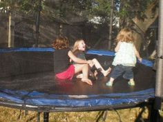 three children playing on a trampoline in the yard