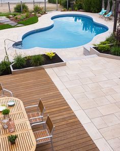 a wooden table sitting on top of a wooden deck next to a swimming pool in a backyard