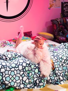 a woman laying on top of a bed in a room with pink walls and decorations