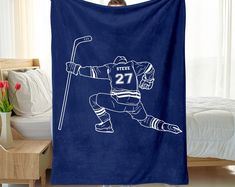 a hockey player with a stick and number 27 on a blue blanket in front of a bed