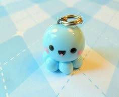 a small blue toy sitting on top of a checkered tablecloth with a metal keychain