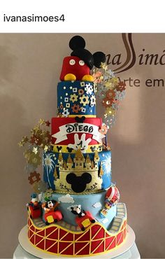 a multi - tiered cake with mickey mouse and other disney characters on it's side