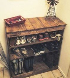 a wooden shelf with shoes and umbrellas on it in the corner of a room