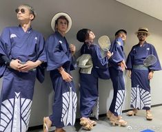 several people in blue kimonos and hats are standing against a wall with their hands on their hips