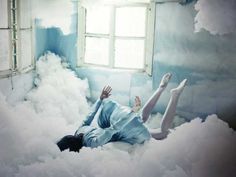 a woman laying in the clouds with her hands up