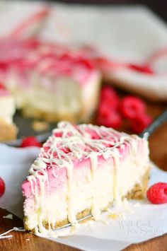 a slice of raspberry cheesecake with white icing and fresh raspberries on the side