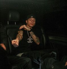 a man sitting in the back seat of a car with tattoos on his arm and chest