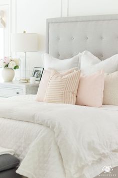 a bed with white sheets and pink pillows