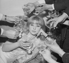 a group of people holding wine glasses in front of each other with their hands on top of the woman's head