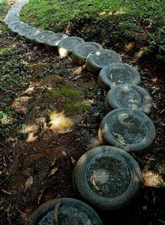 a row of tires sitting on top of a grass covered field next to a forest