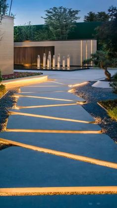 the walkway is lit up at night in front of a building with lights on it