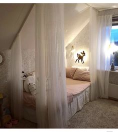 a bedroom with white curtains and pink bedding